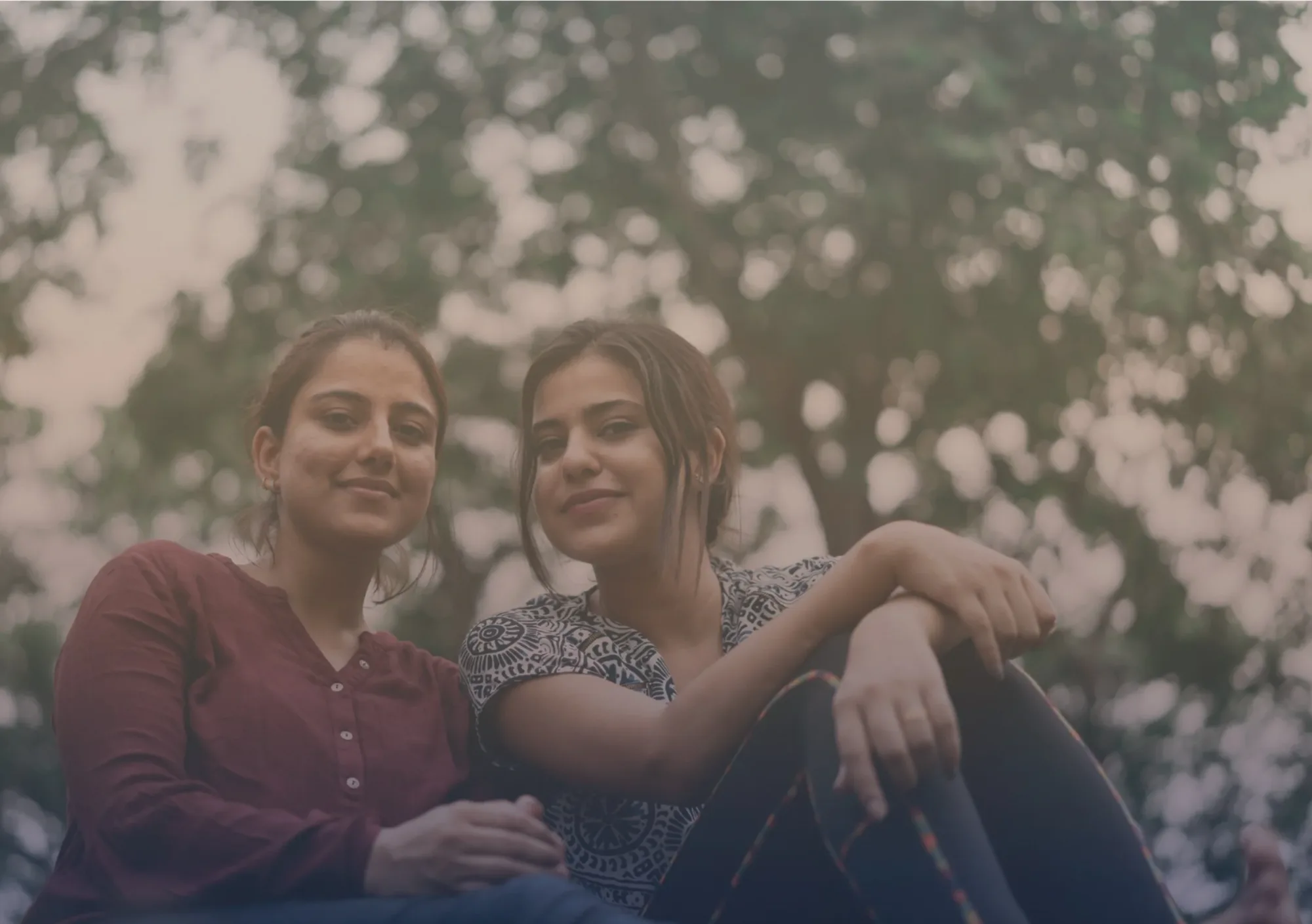 Two young South Asian women laughing together outdoors