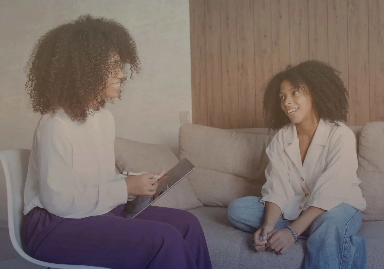Two women talking on a sofa in a bright living room
