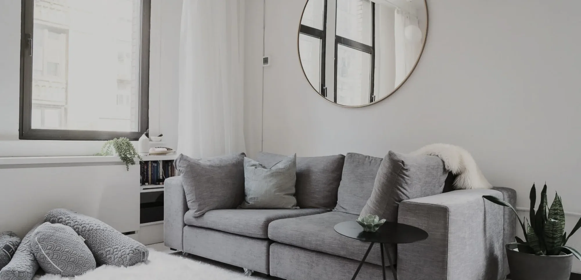 A bright, calm sitting room with a soft sofa and natural light