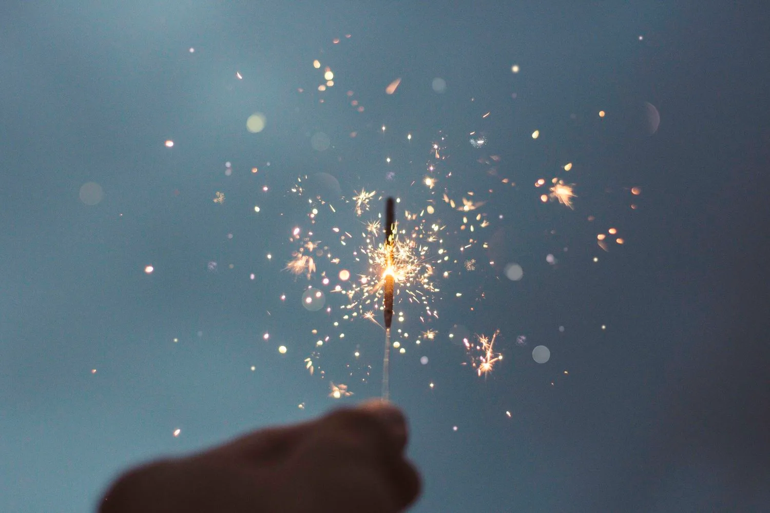Sparkler glowing against a blue evening sky