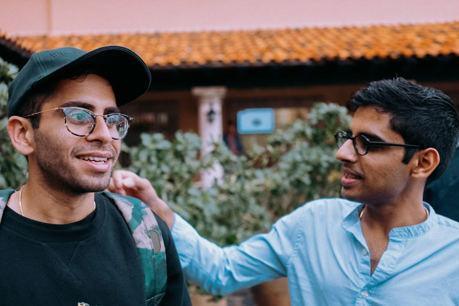 Two young men smiling and talking outside a café