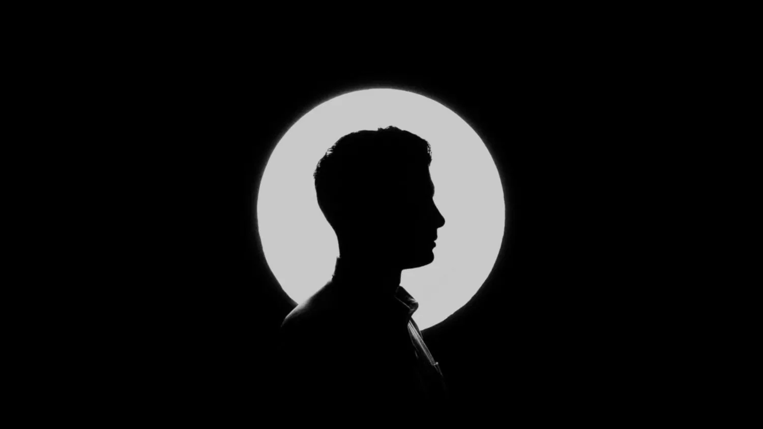 Silhouette of a person’s head in profile against a white circle