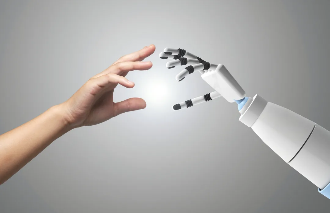 A human hand reaching toward a white robotic hand against a soft gray background