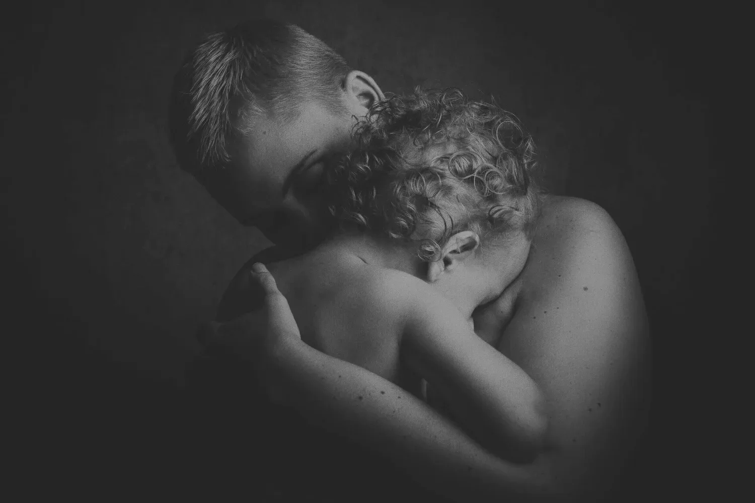 Black-and-white photo of a parent holding a child close