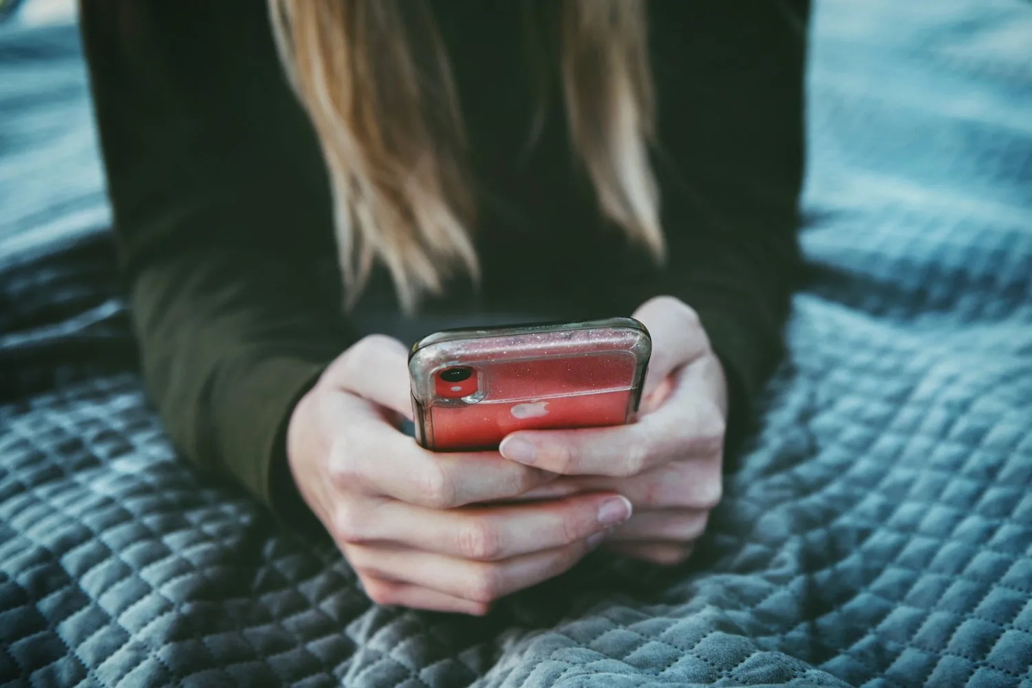 Hands holding a phone over a knit blanket