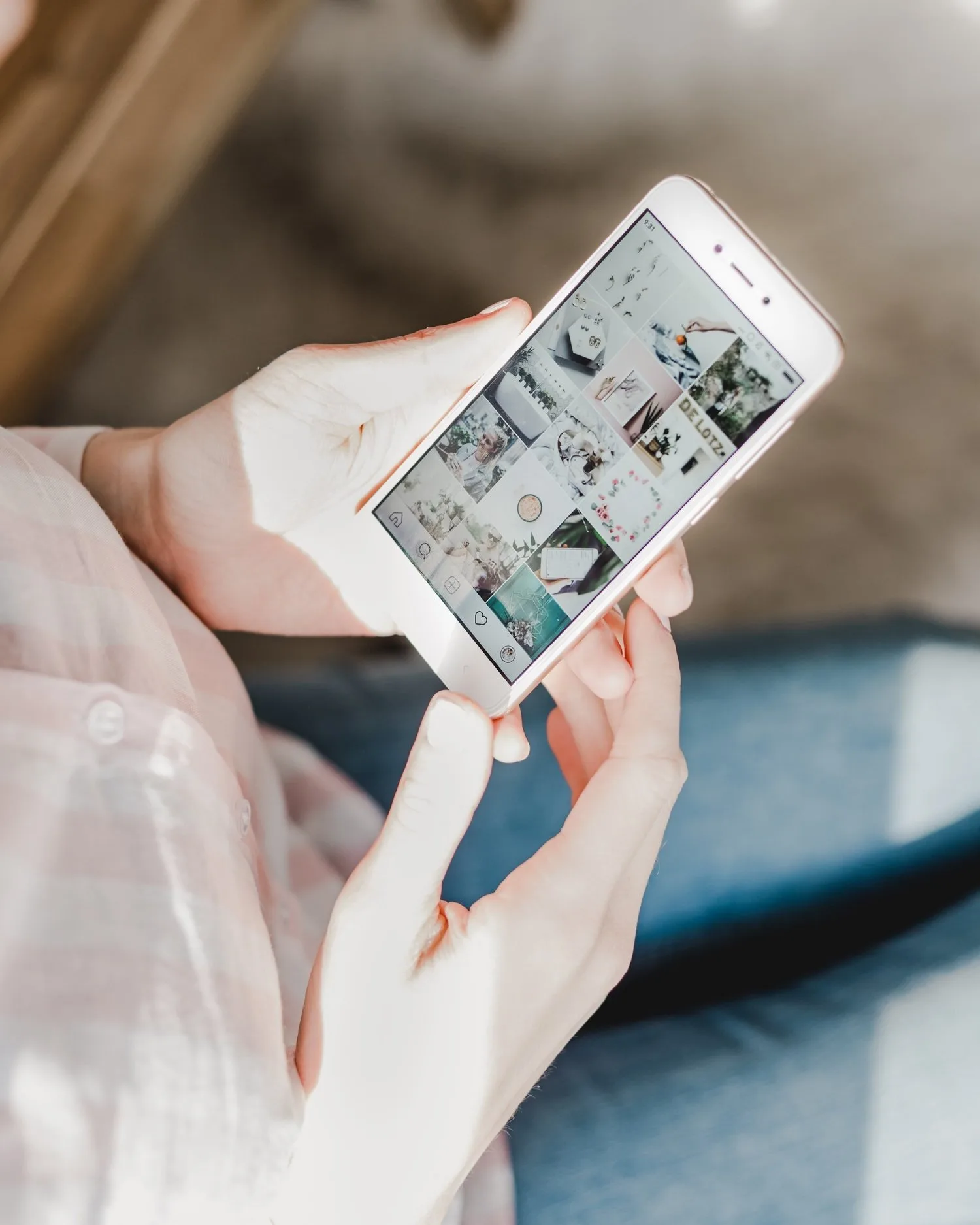 Hand holding a phone displaying a photo feed