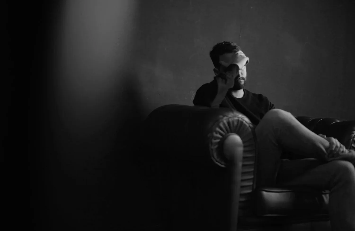 Black-and-white photo of a man sitting alone in a dim room