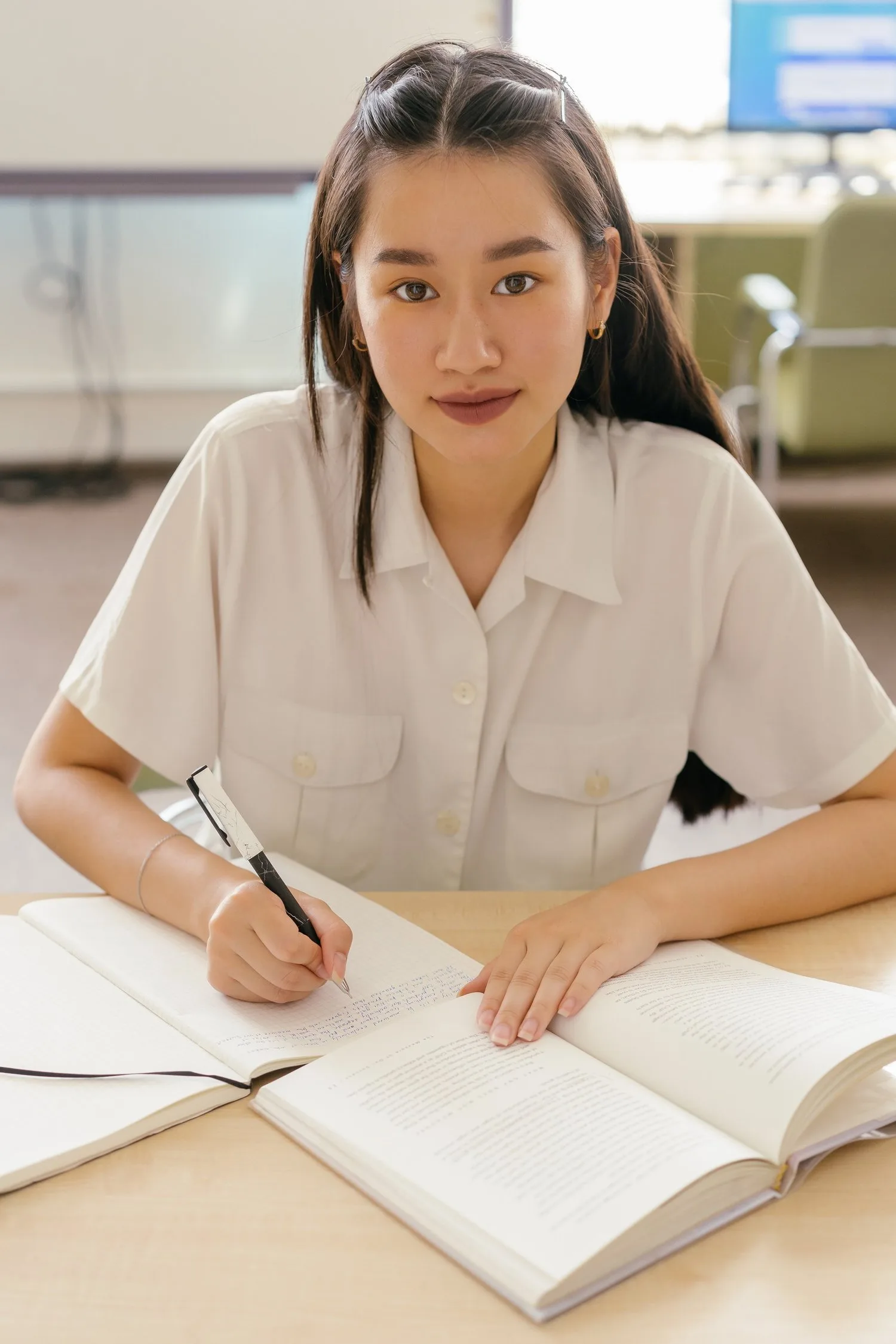Young woman smiling while writing in a notebook at a desk