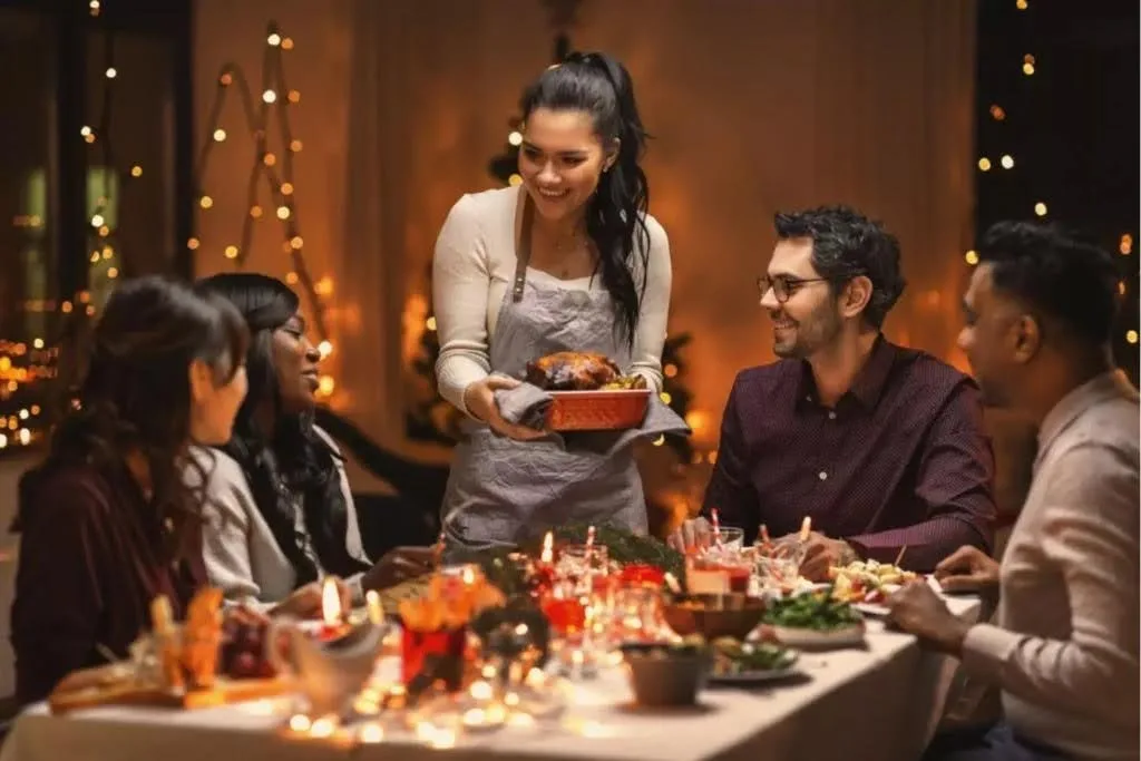 Friends gathered around a candlelit dinner table sharing a holiday meal