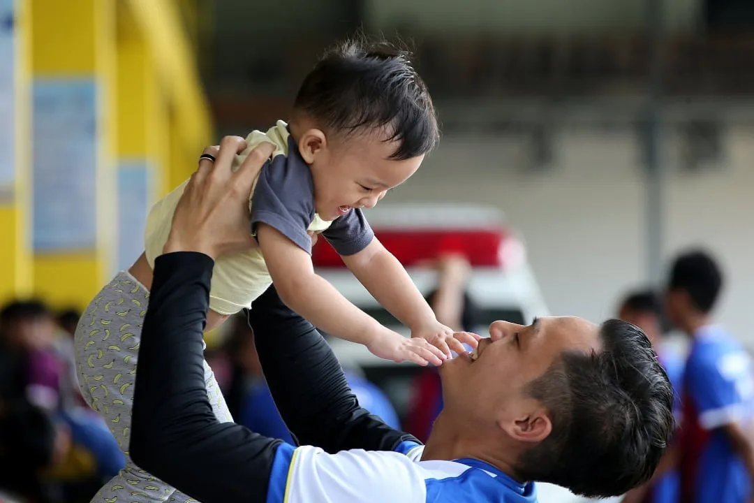 Father lifting his young son into the air, both smiling