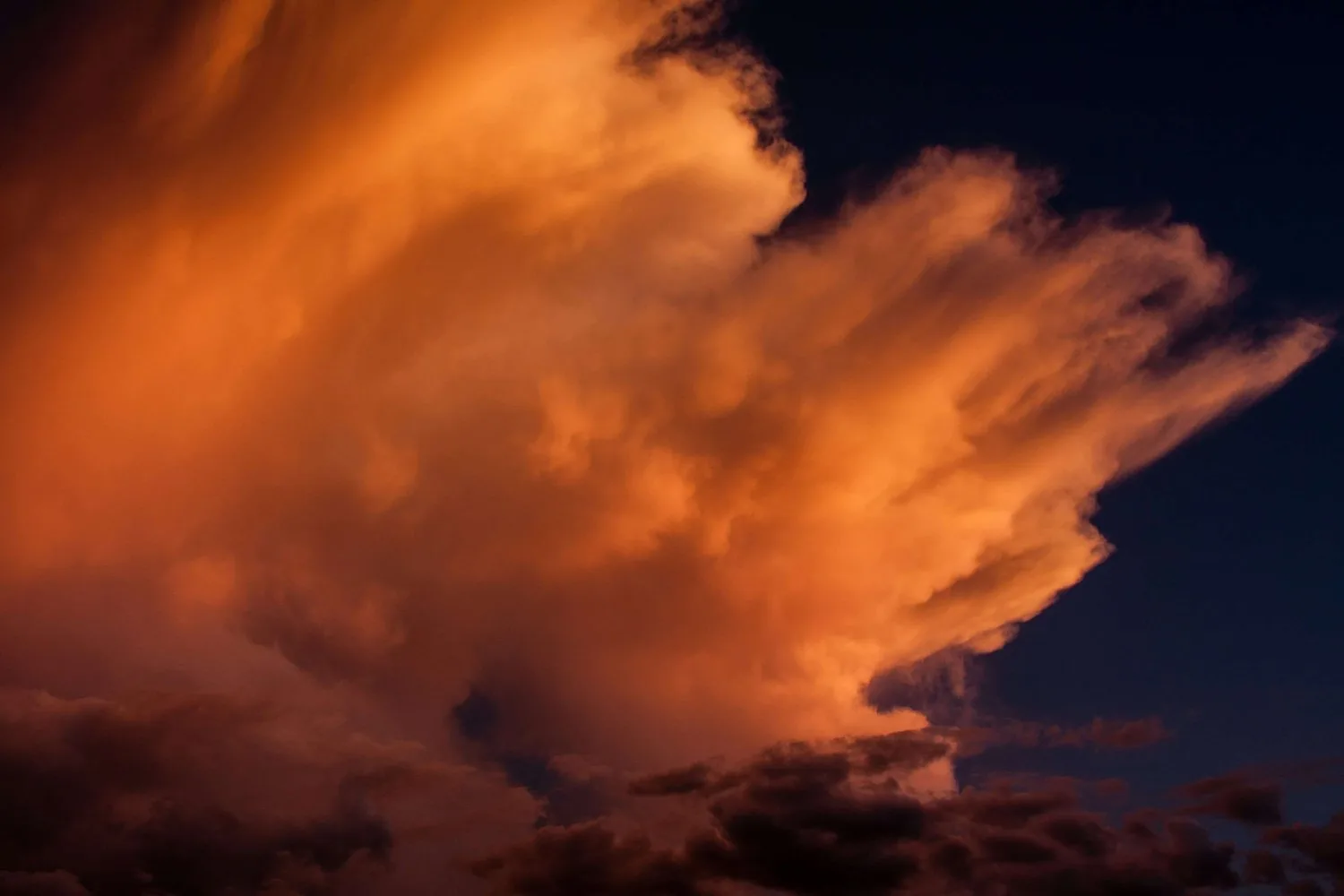 Glowing orange storm cloud against a dark night sky