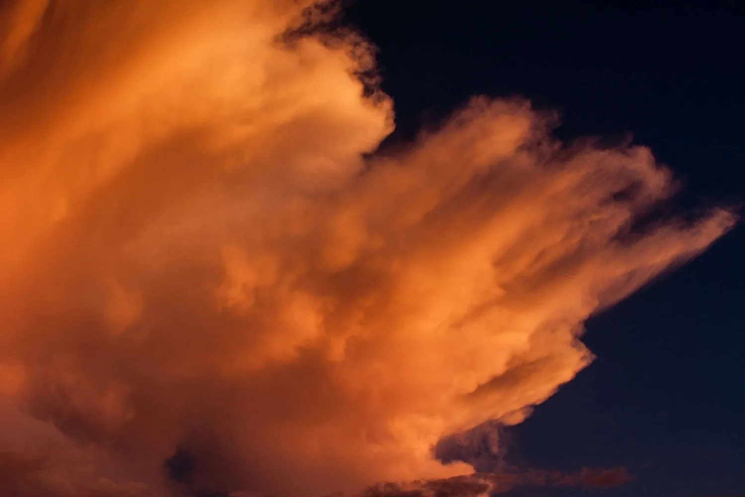 Glowing orange storm cloud against a dark night sky
