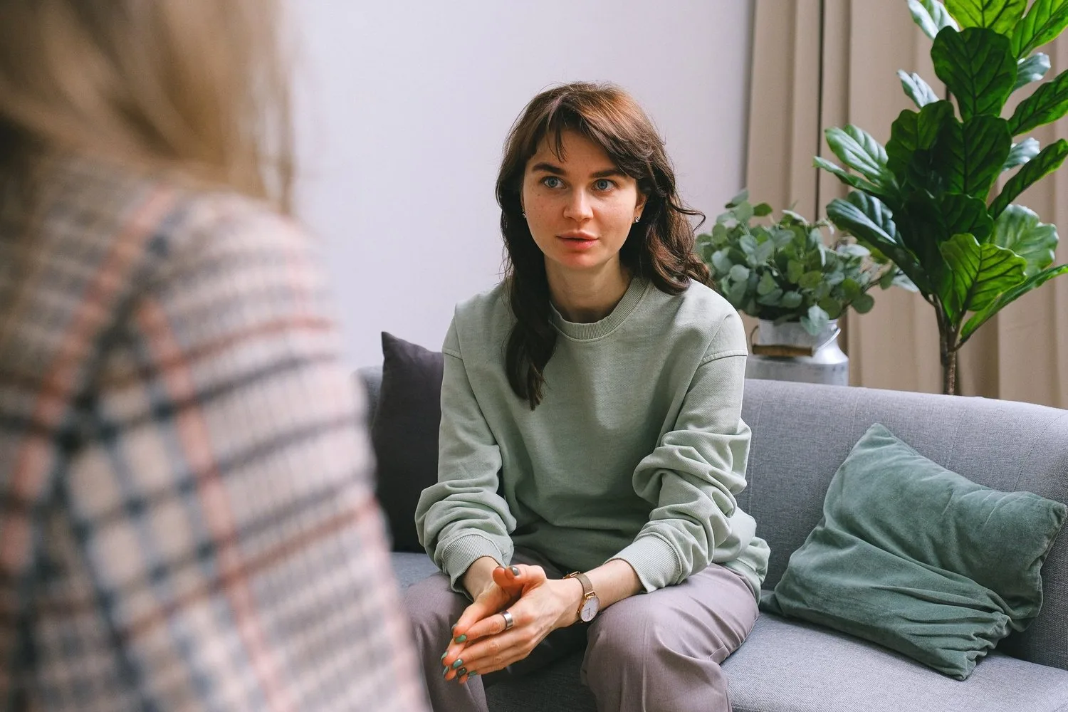 Woman sitting on a sofa listening to someone seated across from her