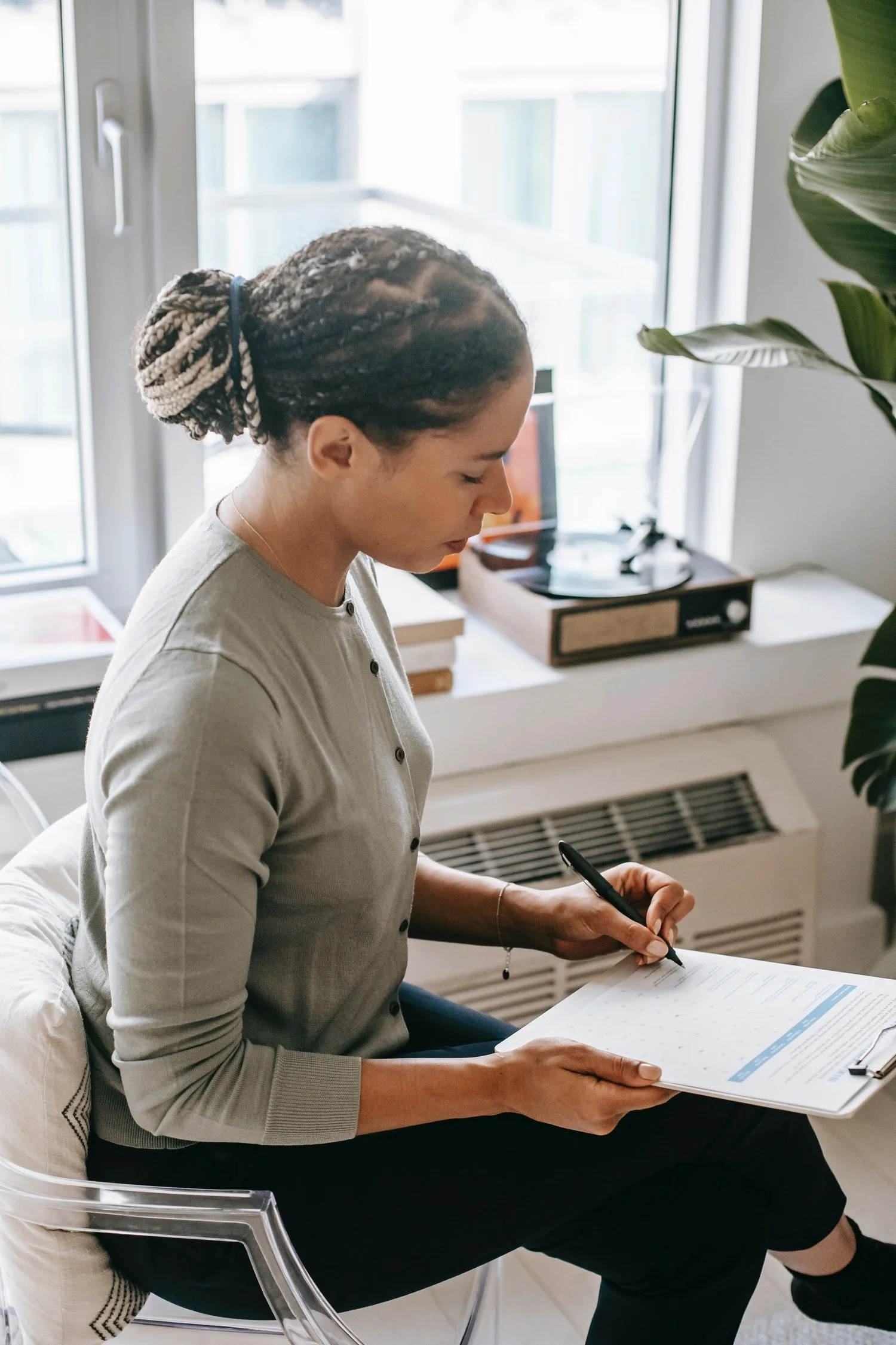 Therapist writing notes on a clipboard in a sunlit office