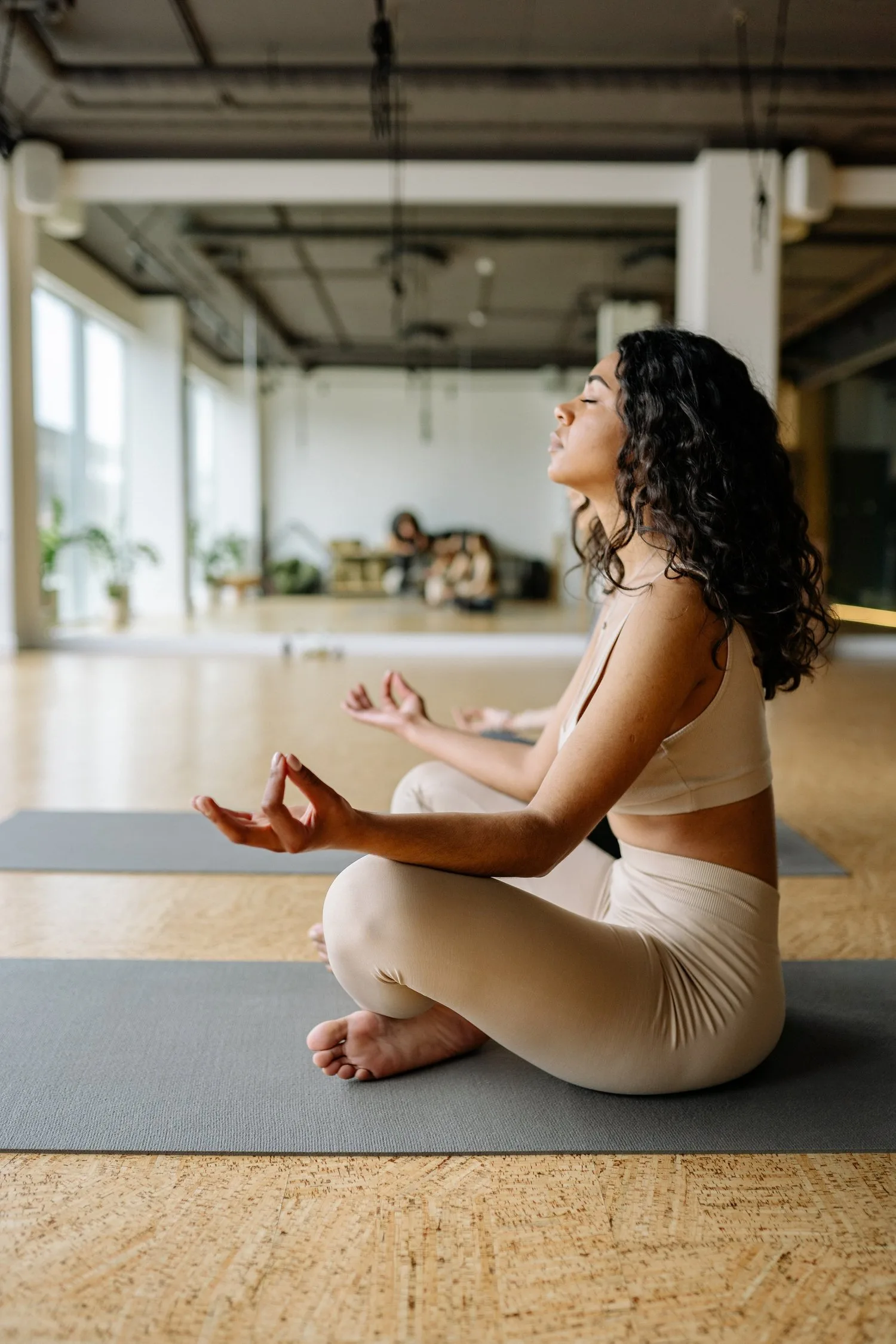 Woman meditating cross-legged on a mat in a spacious loft studio