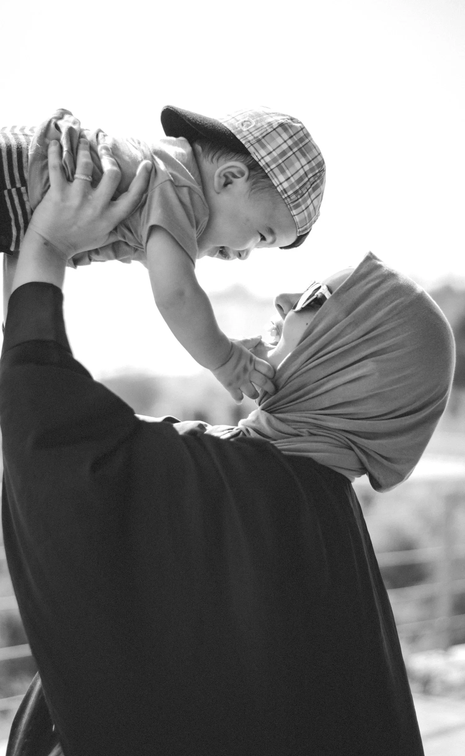 Black-and-white photo of a parent lifting a child into the air