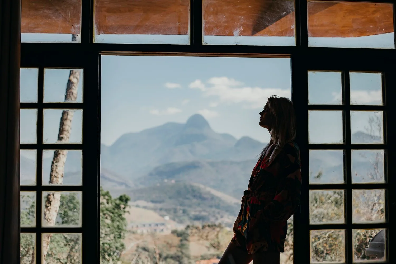 Person silhouetted in a large window overlooking mountains