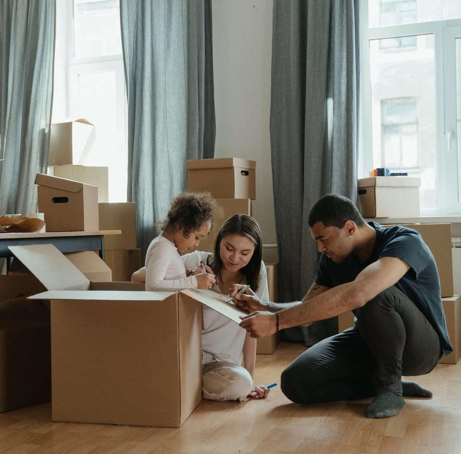 Family unpacking moving boxes together on a living room floor