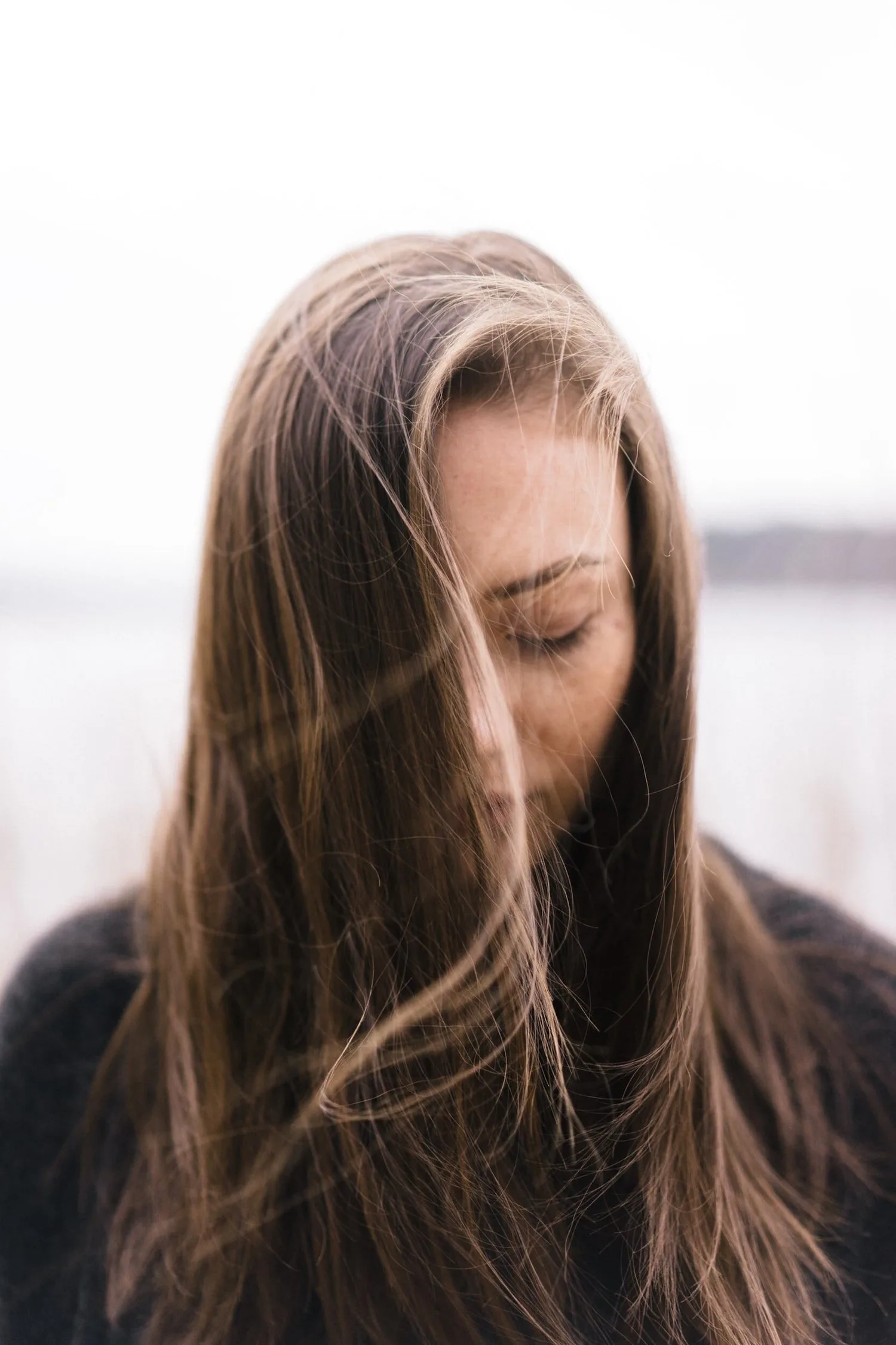 Woman with long hair falling across her face, looking down