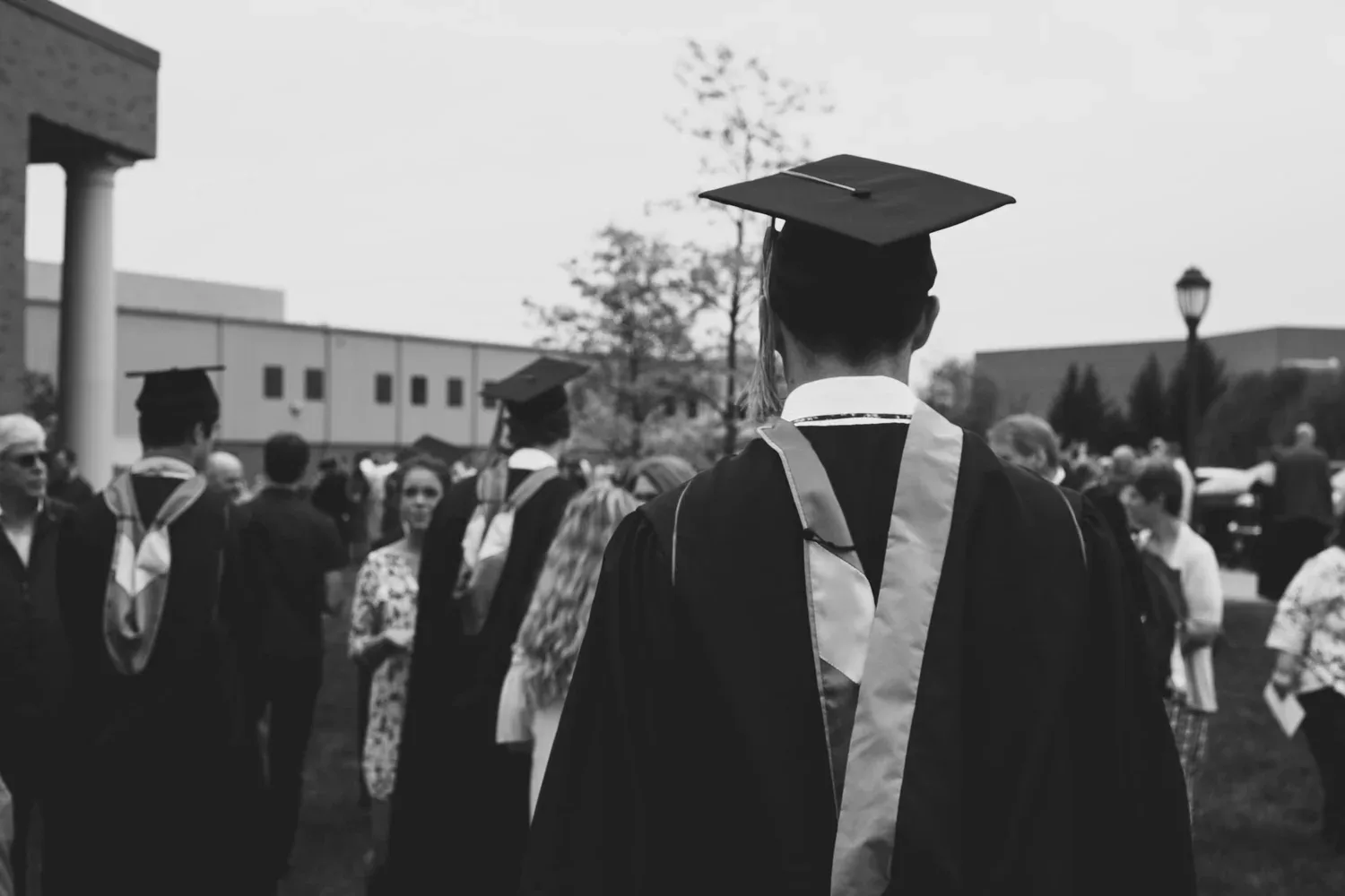 Black-and-white photo of graduates in caps and gowns seen from behind
