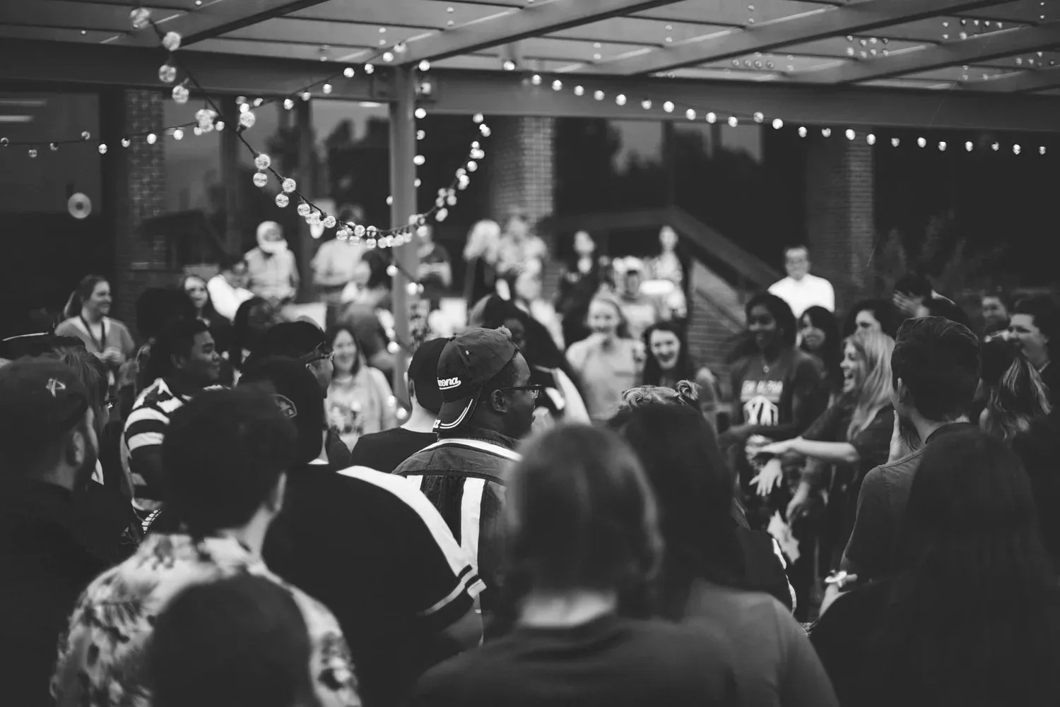 Black-and-white photo of a crowded party under string lights