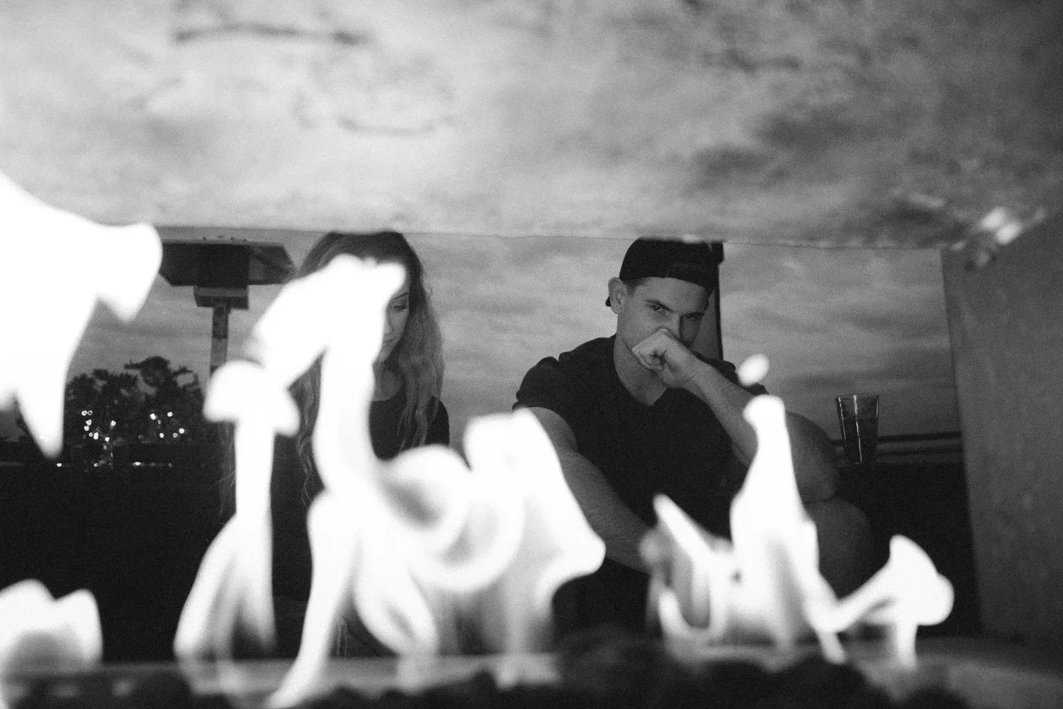 Black-and-white photo of two people sitting by a bright fire