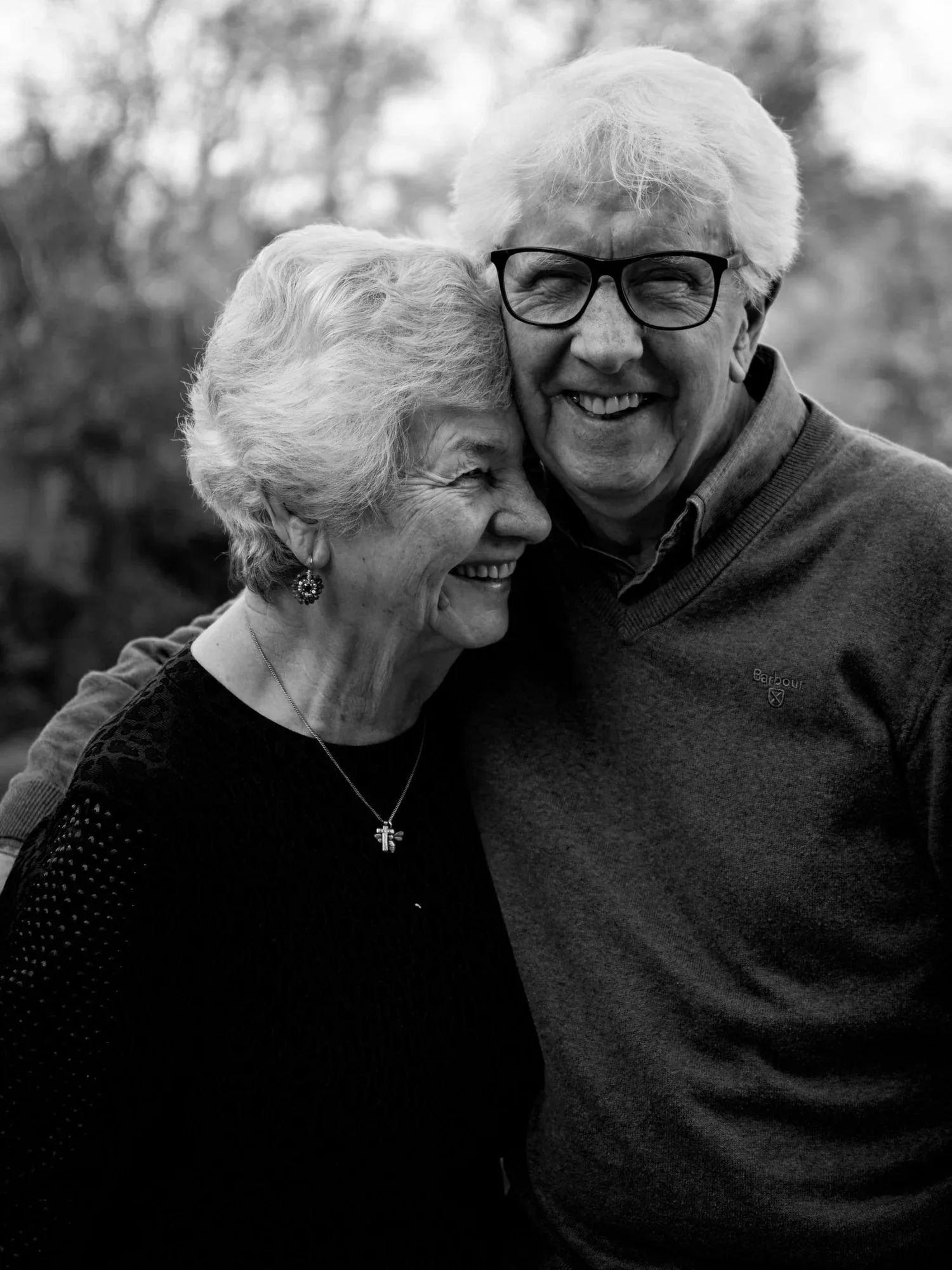 Black-and-white photo of a smiling older couple standing close together