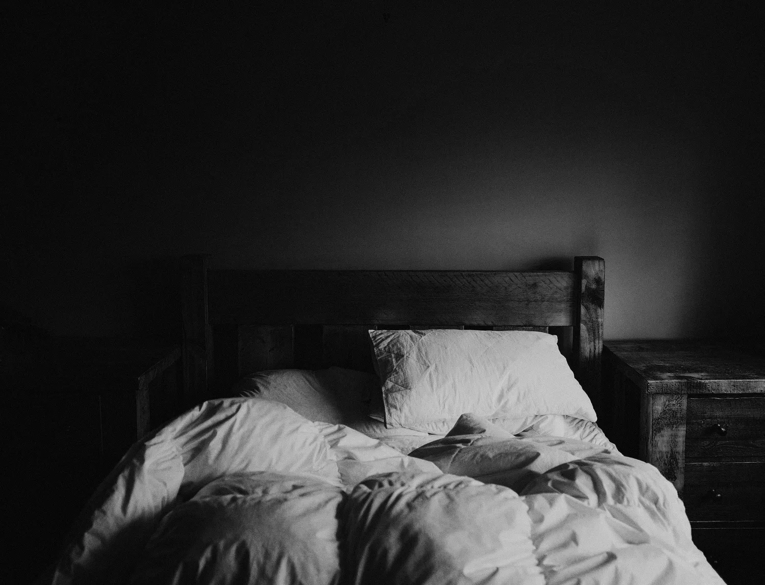 Rumpled bed in a dark bedroom
