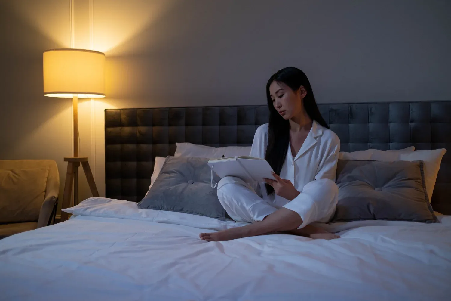 Woman sitting on a bed in a softly lit bedroom