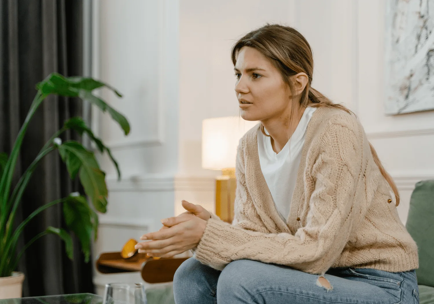 Woman in a cardigan sitting on a sofa in a calm living room