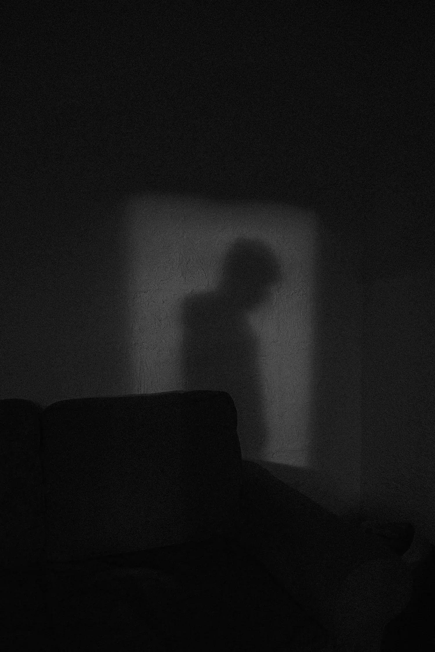 Shadow of a person cast on a wall in a dark room