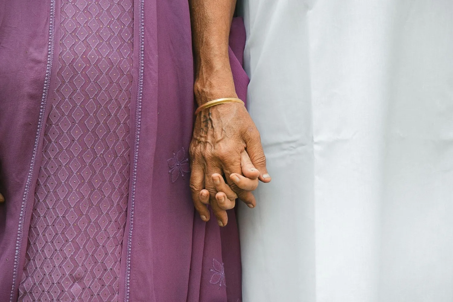 Two people in traditional clothing holding hands, shown from the waist down