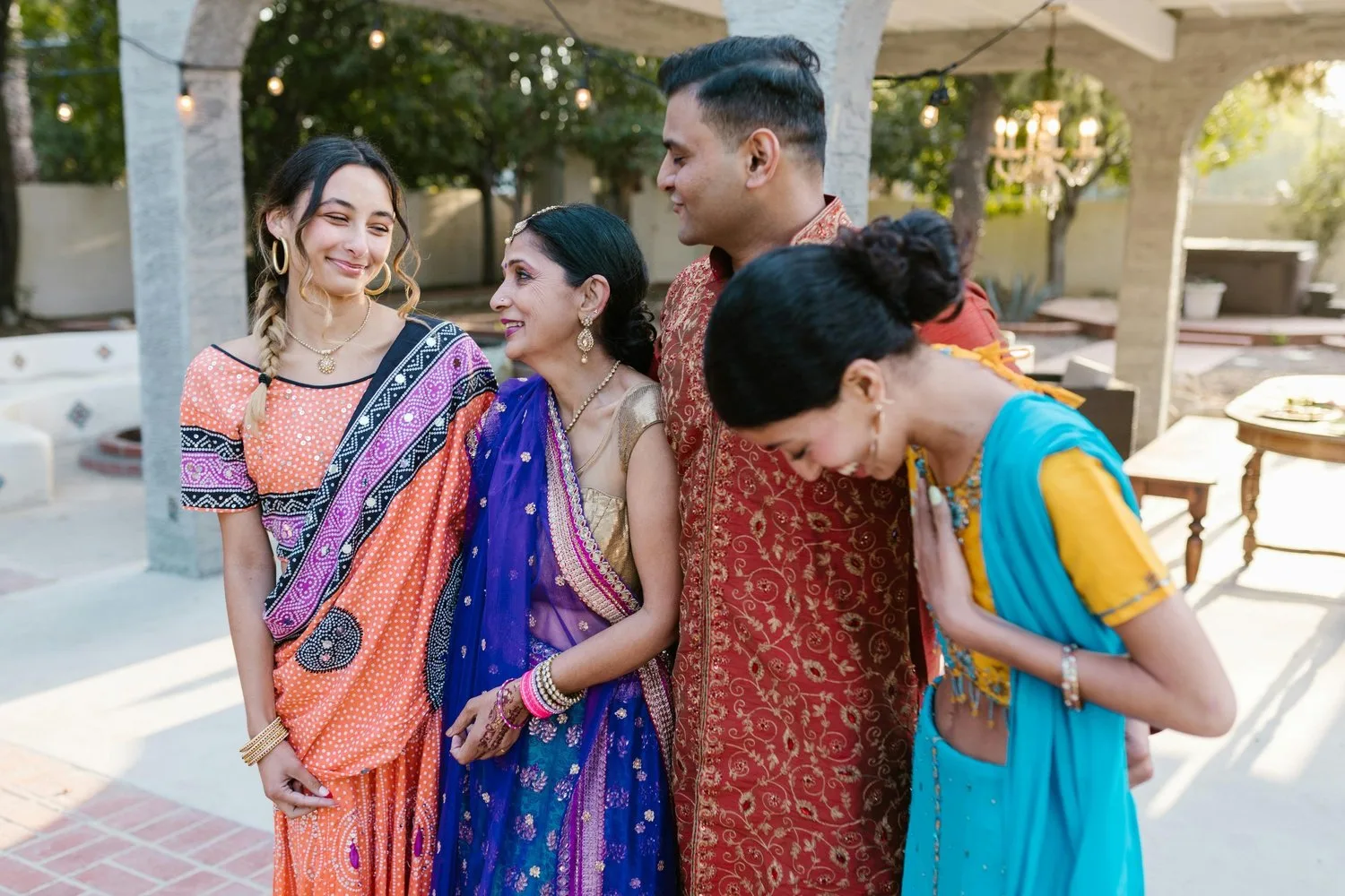 South Asian family in saris and traditional dress laughing together outdoors