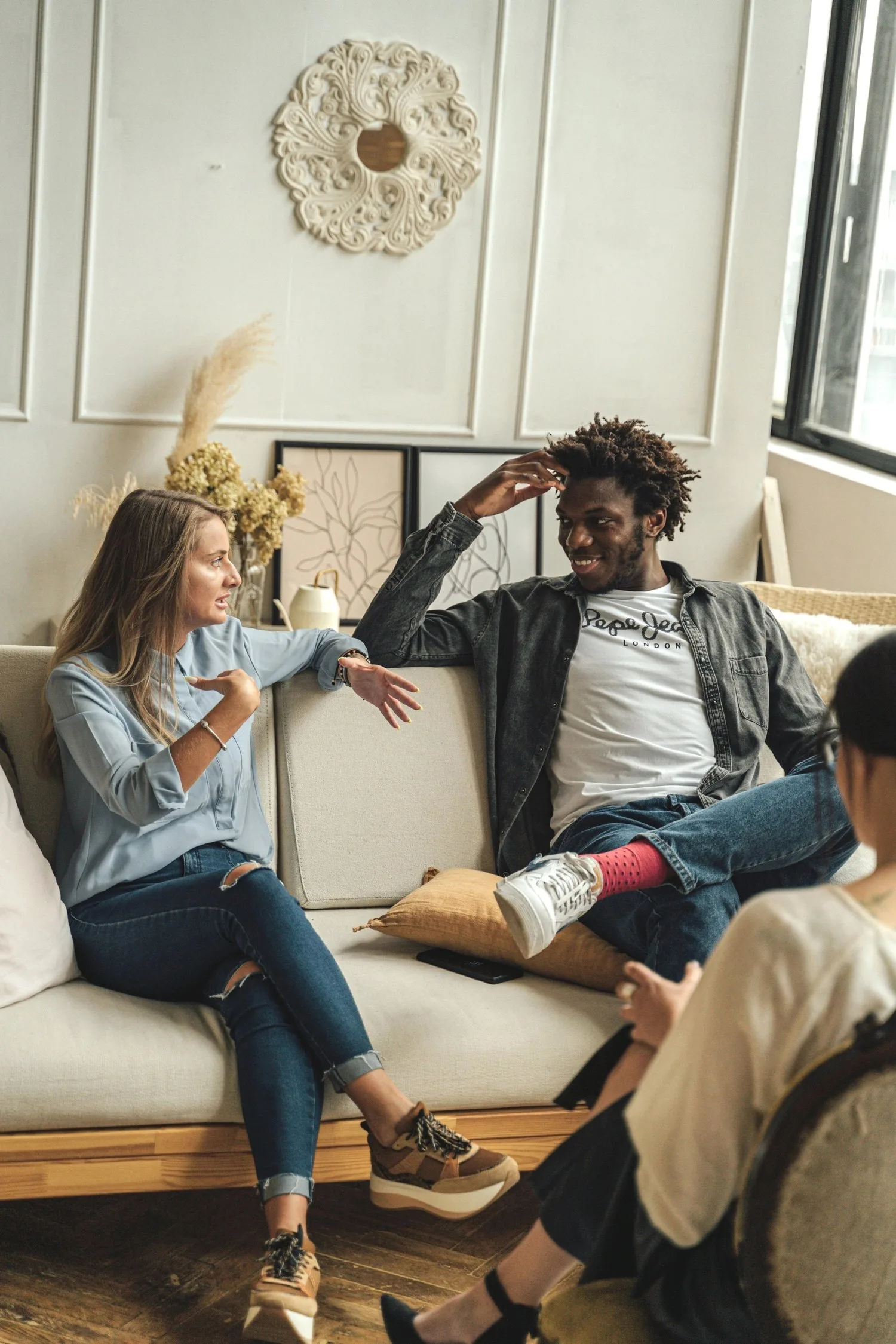 Two young women chatting on a sofa in a bright apartment