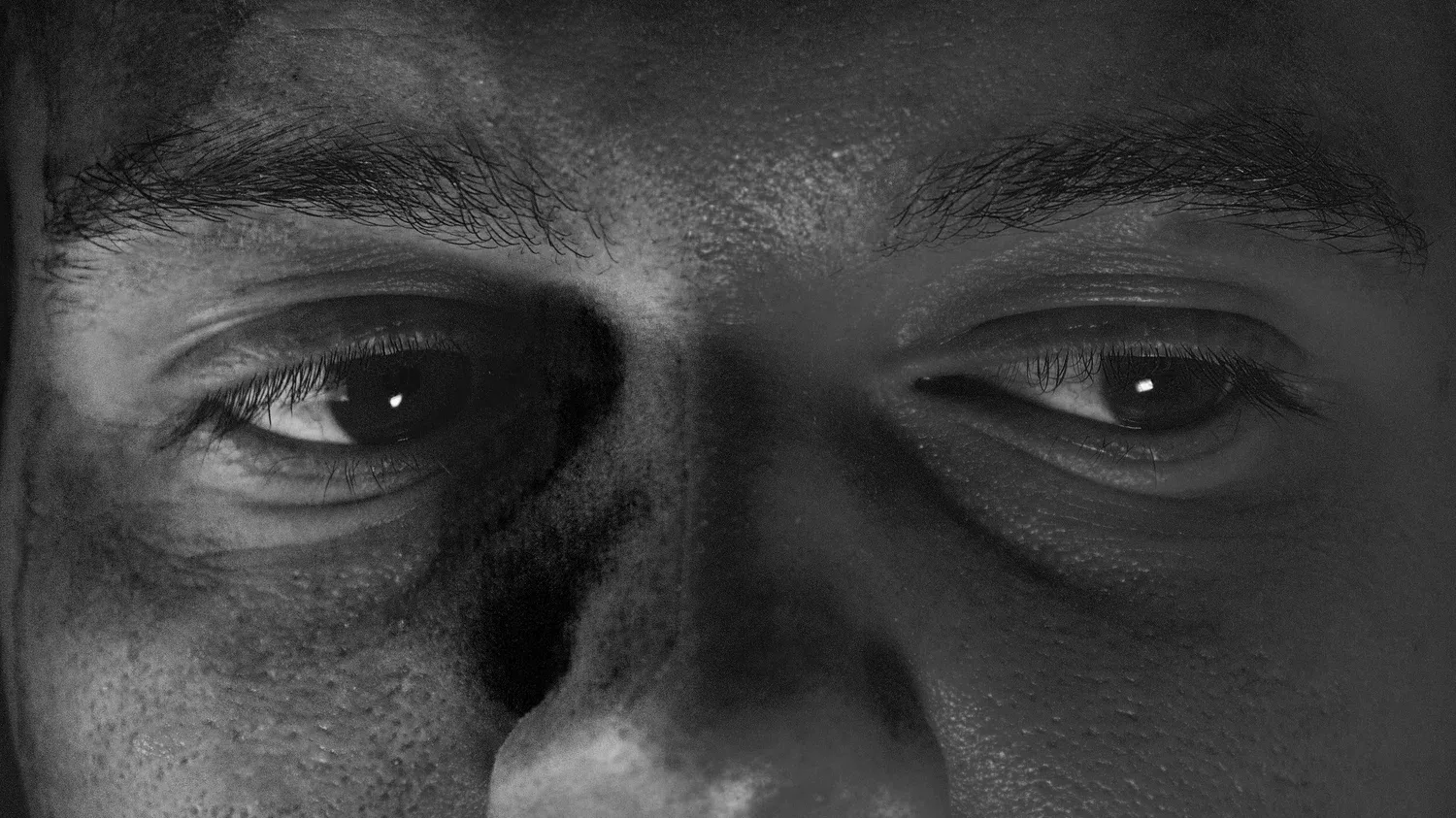 Black-and-white close-up of a man’s eyes in shadow