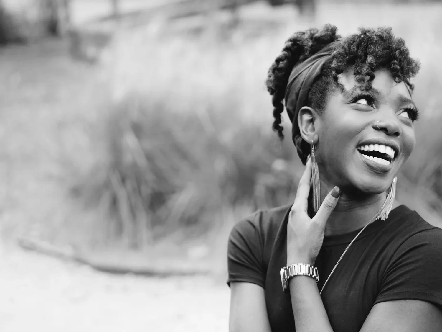 Black-and-white photo of a smiling woman with a headband looking up