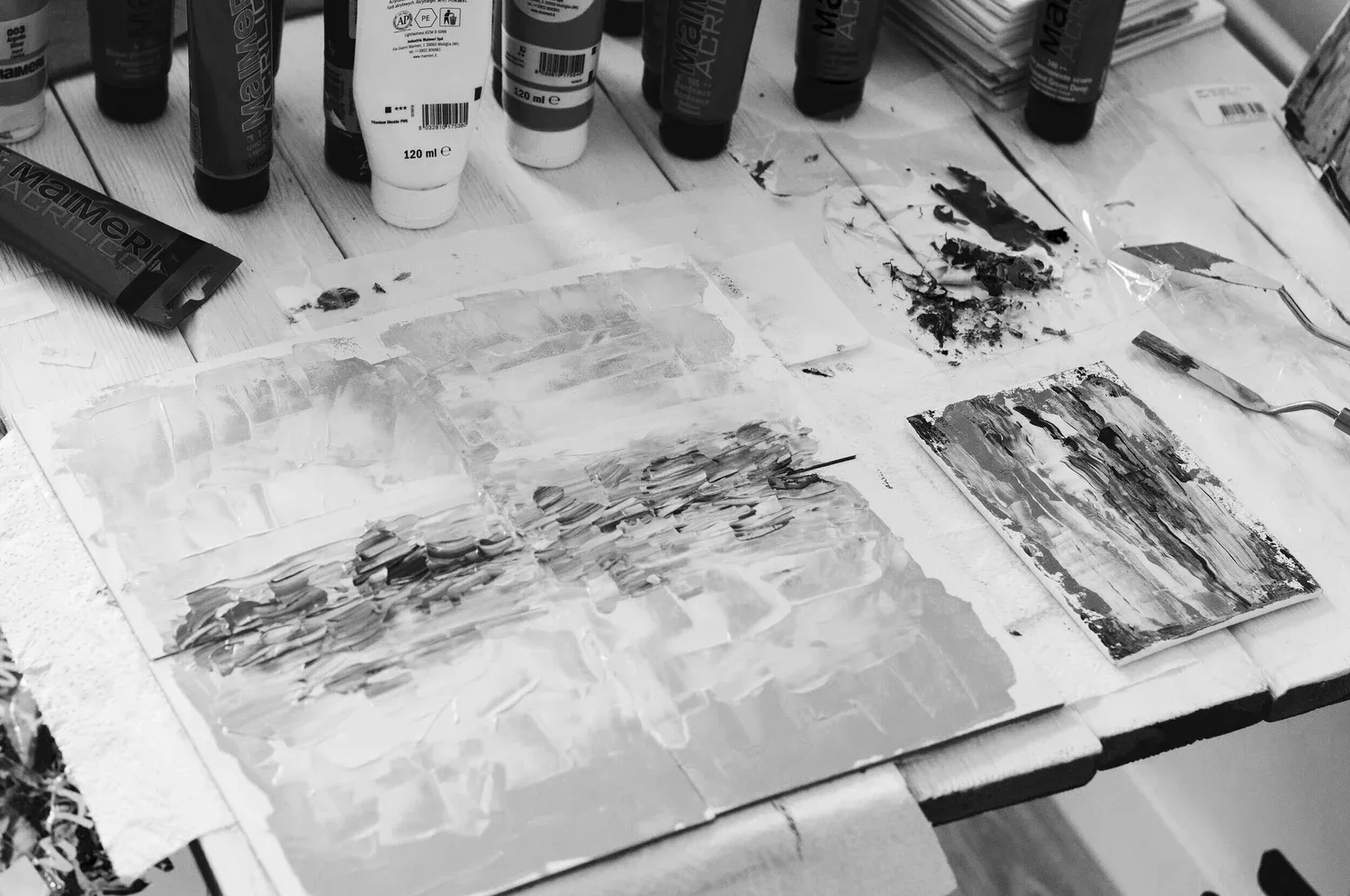 Paintbrushes and abstract ink paintings spread across a table