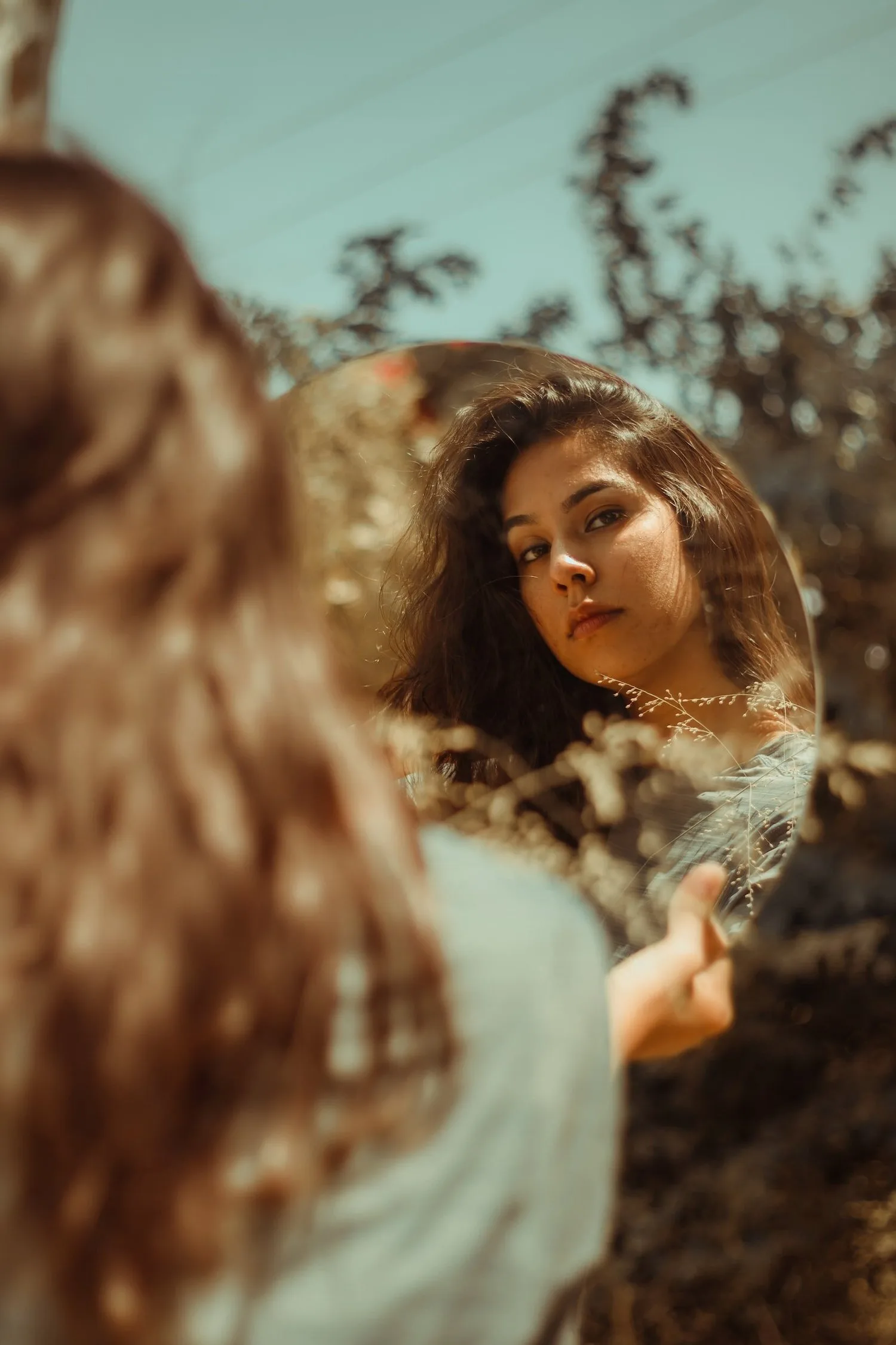 Woman with long hair looking back over her shoulder among greenery