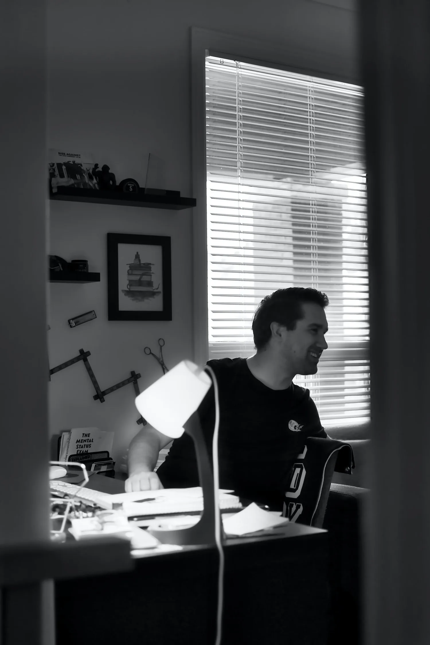 Man working late at a desk lit by a lamp in a dark home office