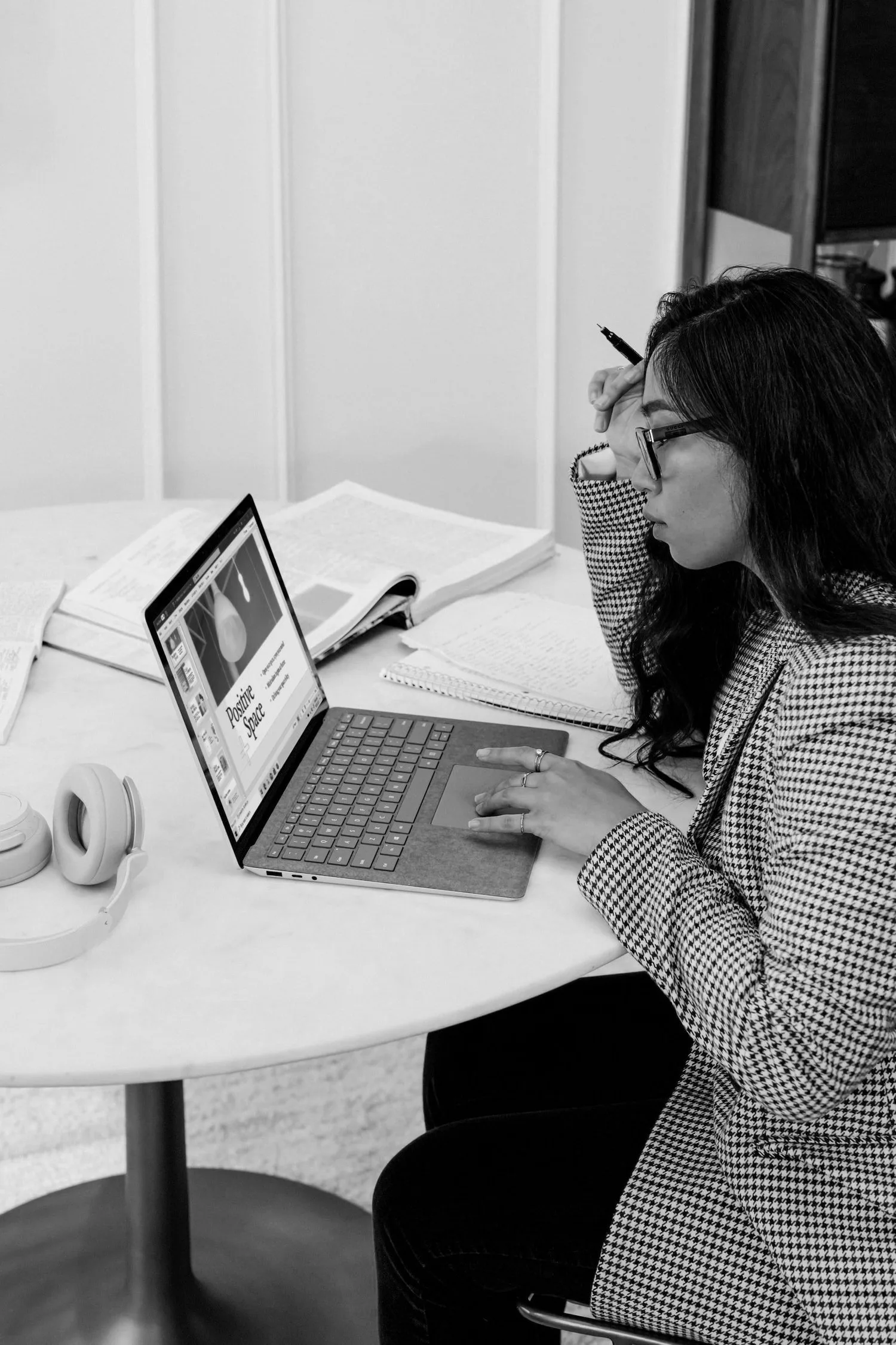 Black-and-white photo of a woman working on a laptop at a desk