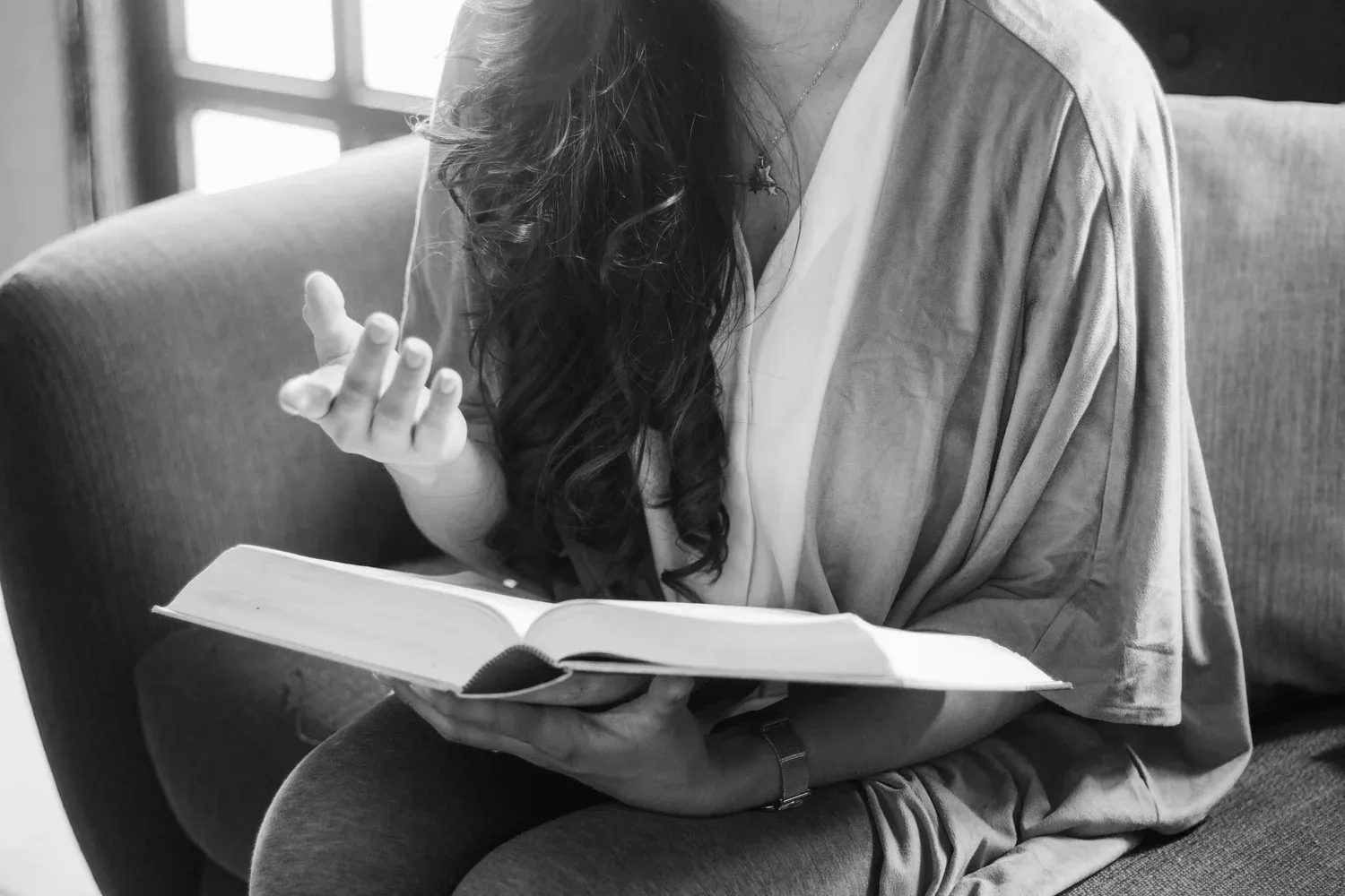 Black-and-white photo of a woman reading a book in bed