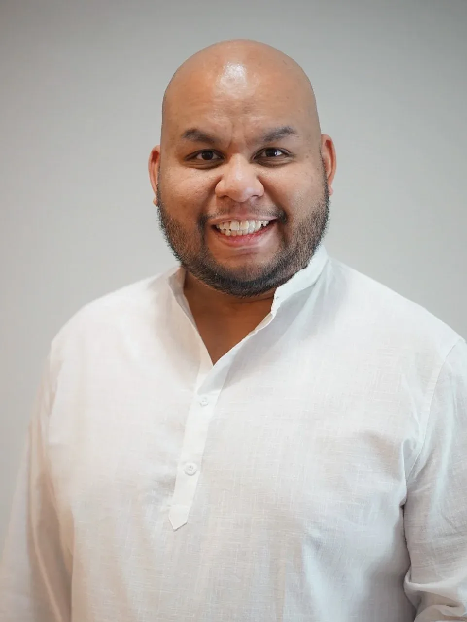 Smiling man in a white shirt against a light gray background
