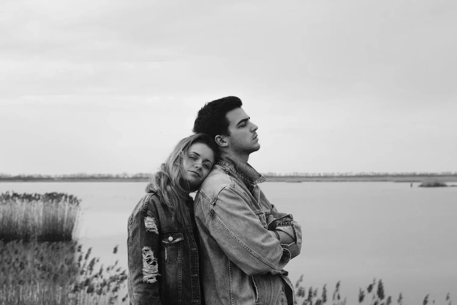 Black-and-white photo of a couple embracing by a lake