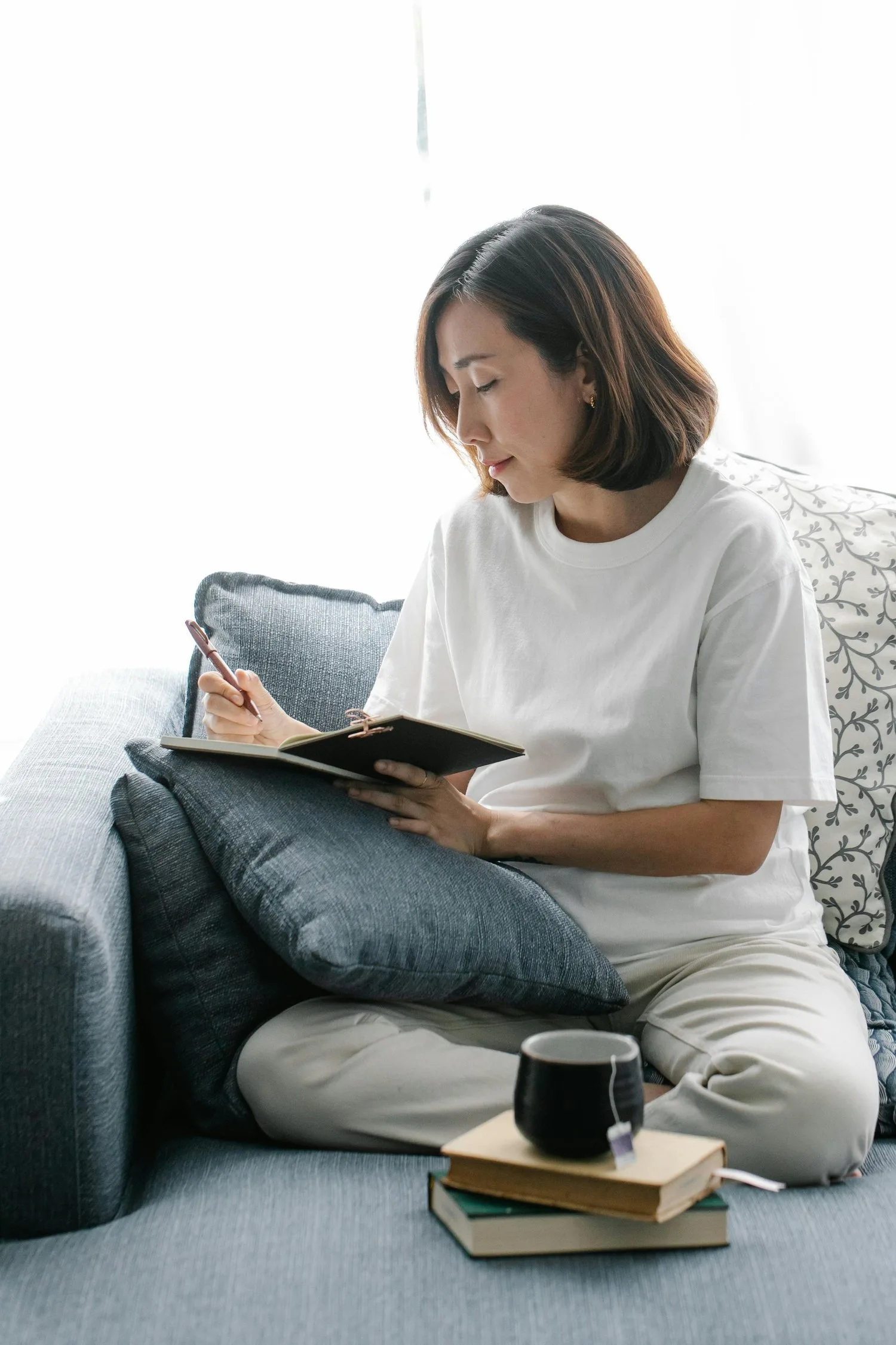 Young woman sitting on the floor reading a book beside a mug