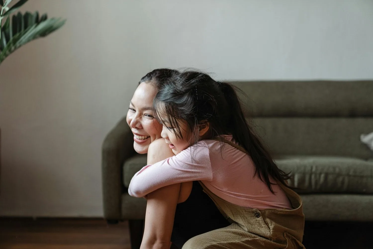 Two young girls hugging each other and laughing on a sofa