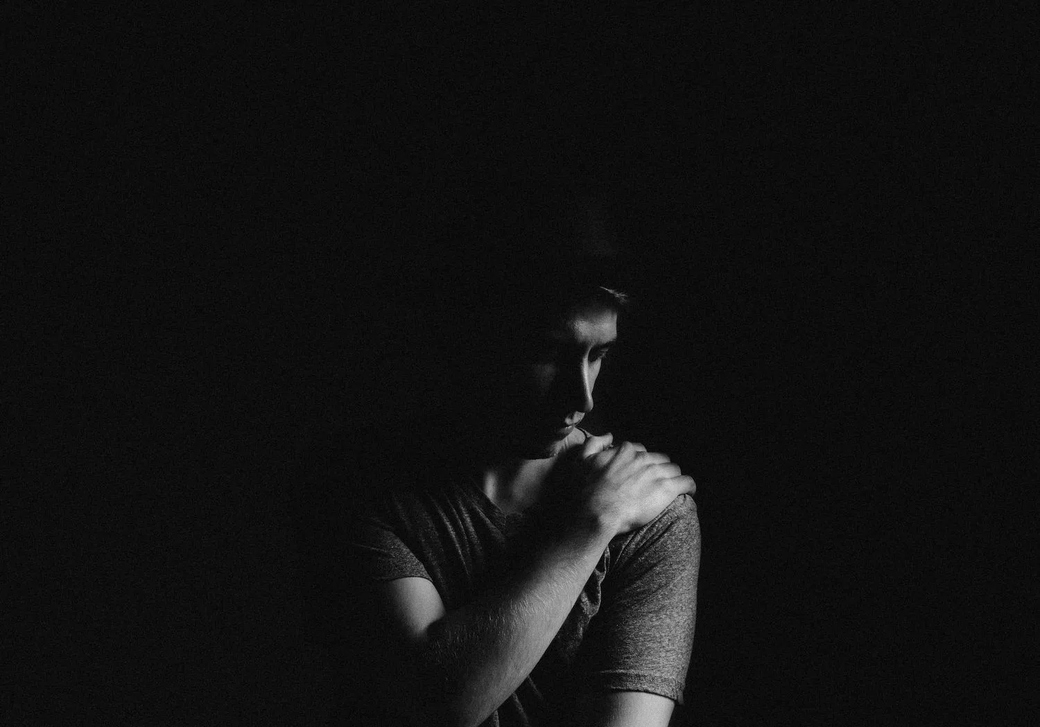 Person sitting in shadow with head bowed