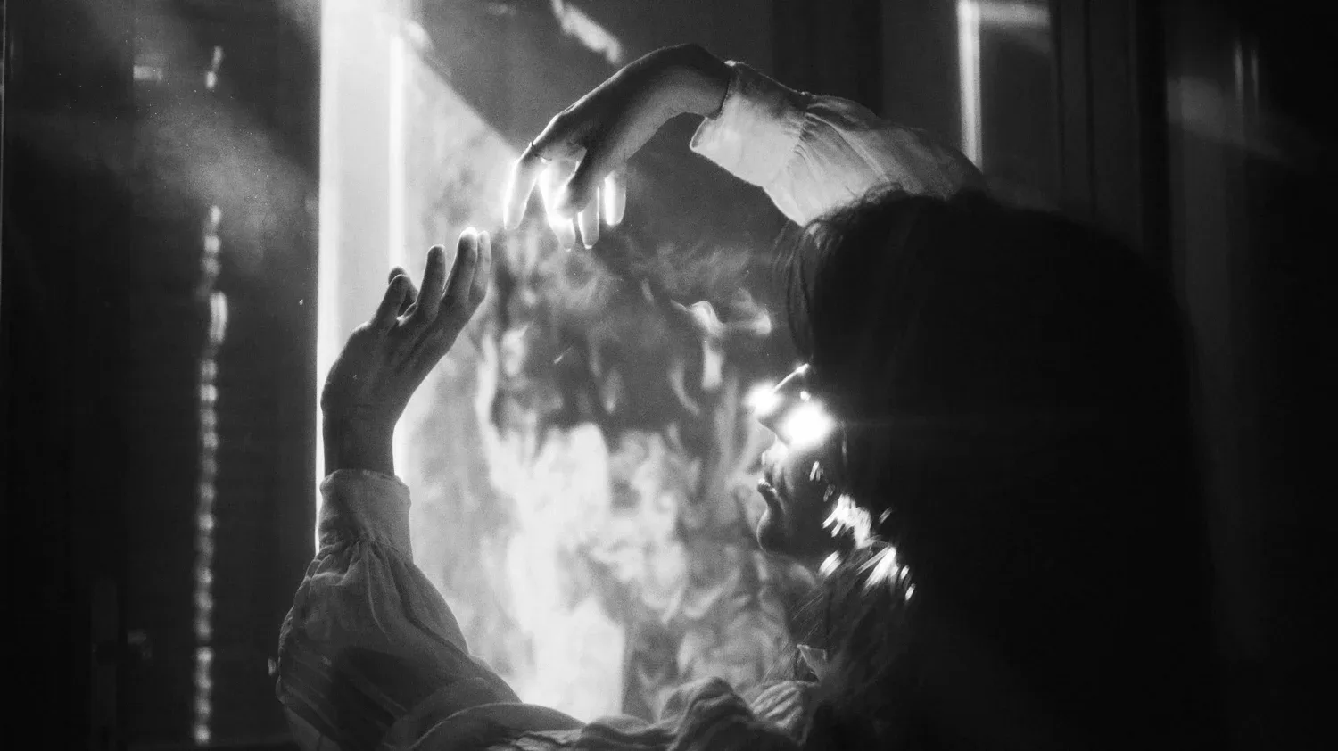 Black-and-white photo of a figure beside a bright light in darkness