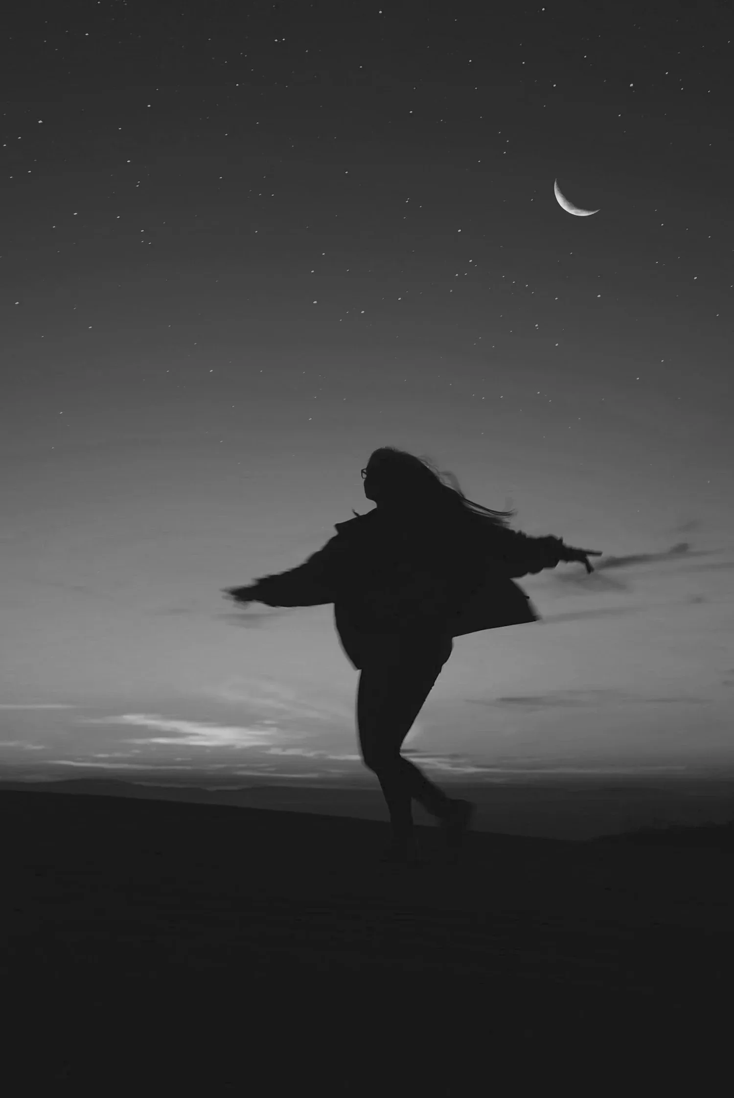 Black-and-white silhouette of a person leaping under a crescent moon