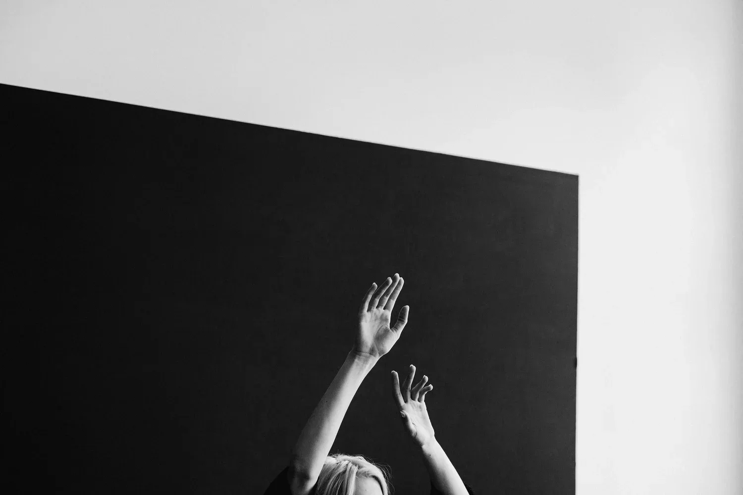 Black-and-white photo of a hand reaching up toward a dark wall