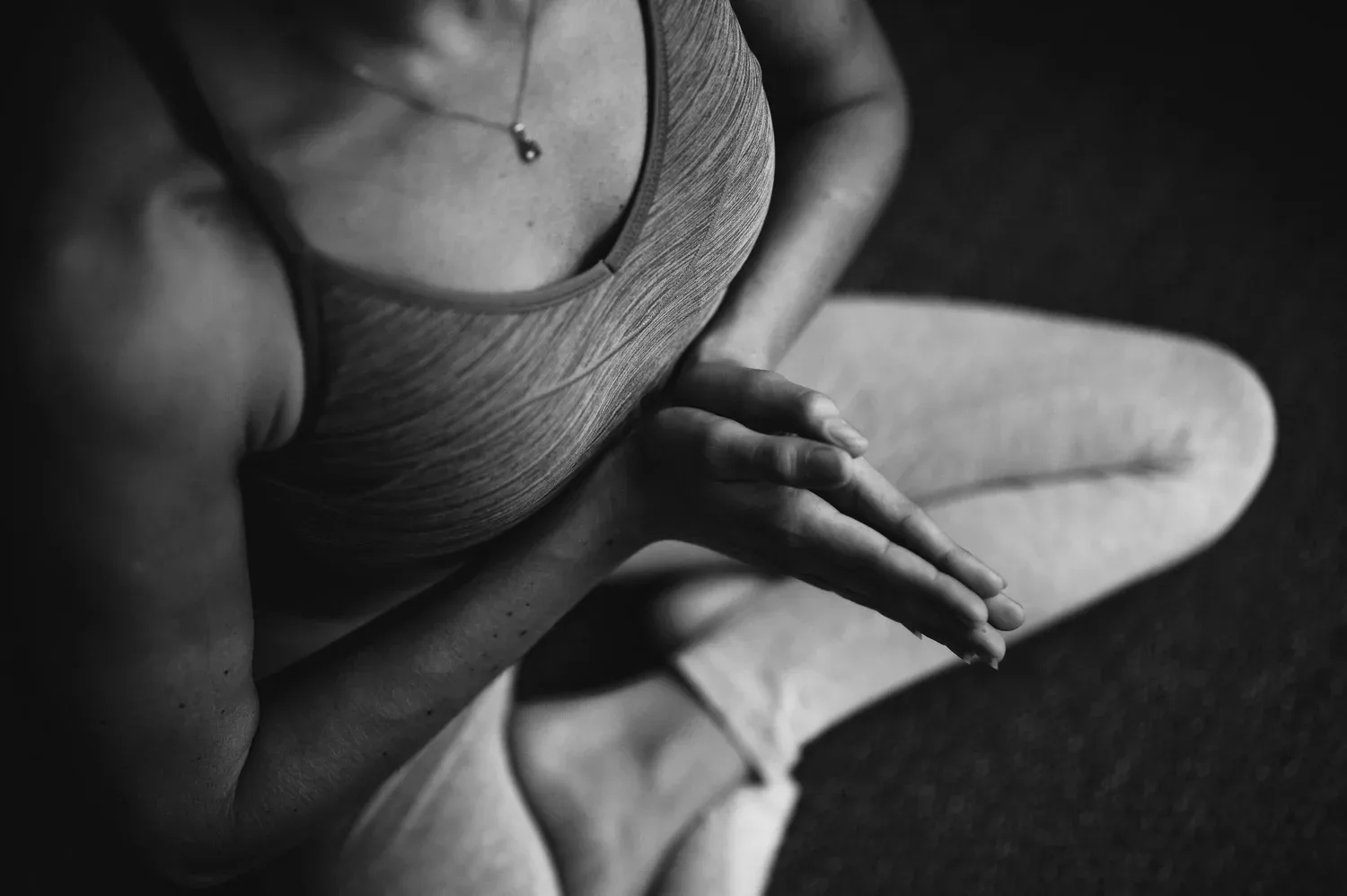 Black-and-white close-up of a person sitting with hands resting on their knees